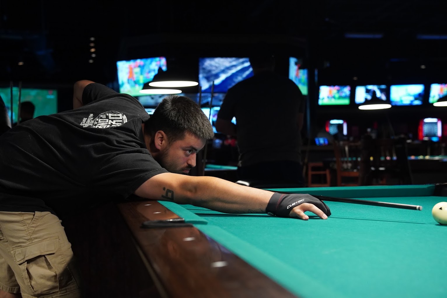 Player leaning low along the rail, sighting down the cue during league night at Fast Eddie's Braun.
