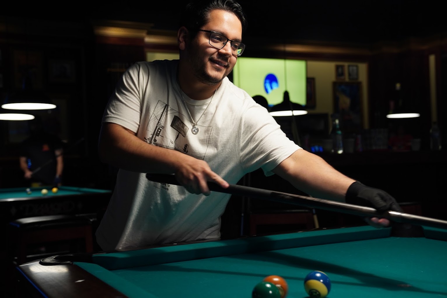 Player smiling as they set up over the rail, cue resting across the cloth.